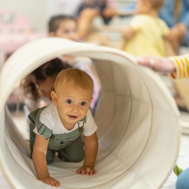 infant crawling through a toy tunnel