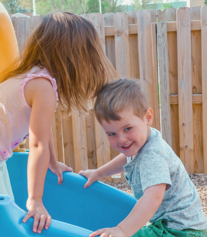 a boy and girl playing on a slide outside at ChildScape