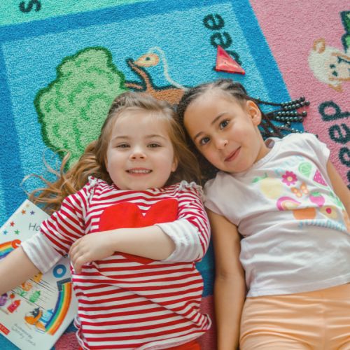 Preschoolers laying on the floor with a book