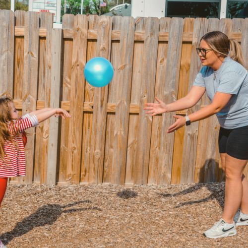 teacher playing with preschooler outside