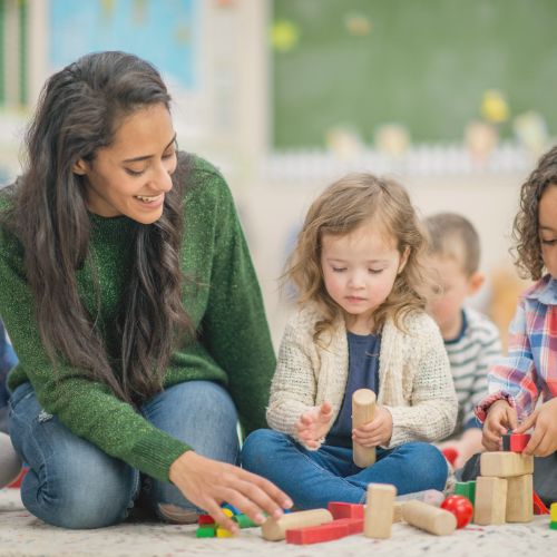 toddlers playing with blocks with their teacher